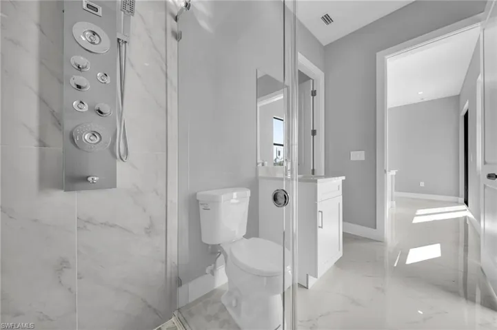 Full bath with vanity, a marble finish shower, and light marble finish floors