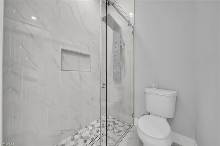 Bathroom featuring toilet and a marble finish shower