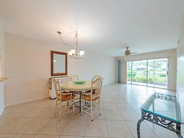 Dining area with light tile patterned flooring and ceiling fan with notable chandelier