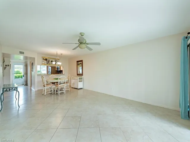Dining space with ceiling fan with notable chandelier and light tile patterned floors