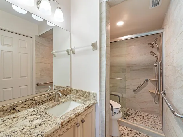 Bathroom with vanity, walk in shower, and toilet