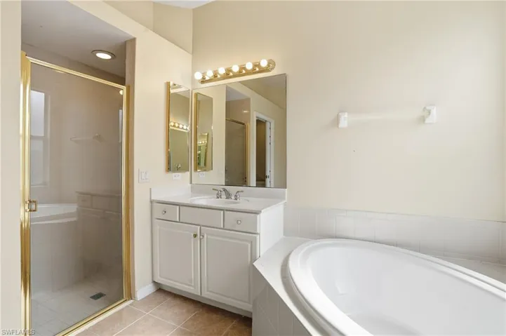 Bathroom featuring light tile patterned floors, a garden tub, vanity, and a stall shower - Virtually Edited Image