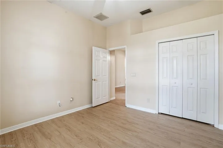 Unfurnished bedroom with light wood-style flooring and a closet - Virtually Edited Image