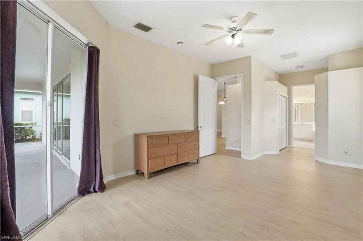 Unfurnished bedroom with light wood-style floors, a ceiling fan, access to exterior, and ensuite bathroom - Virtually Edited Image