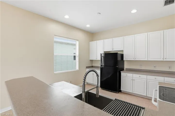 Kitchen featuring white cabinetry, freestanding refrigerator, recessed lighting, light tile patterned flooring, and white electric range - Virtually Edited Image