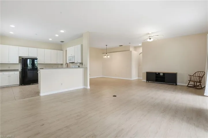 Unfurnished living room with recessed lighting, a chandelier, light wood-style floors, and ceiling fan - Virtually Edited Image