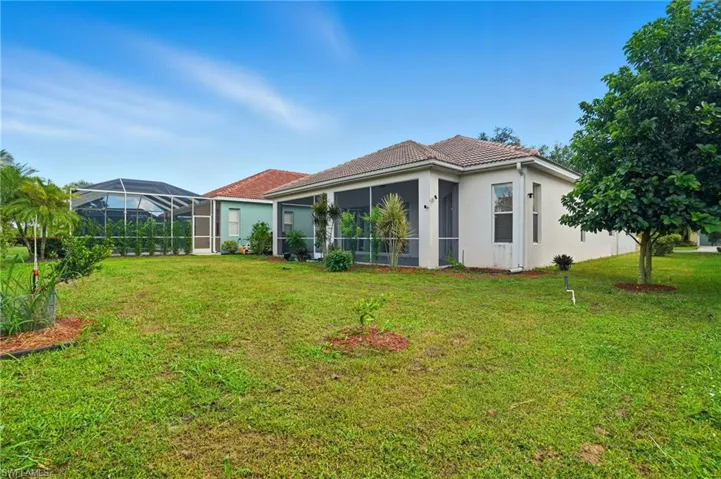 Rear view of property featuring a sunroom, a lawn, stucco siding, and glass enclosure - Virtually Edited Image