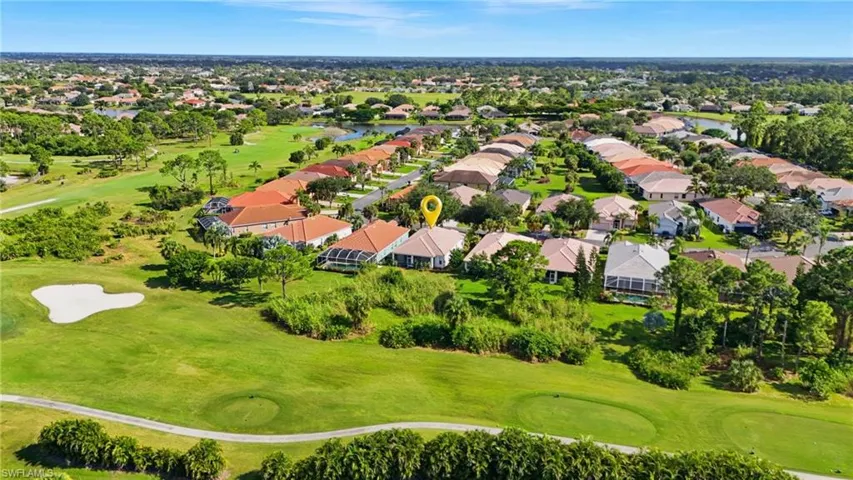 Aerial view of residential area featuring a golf course and a nearby body of water - Virtually Edited Image