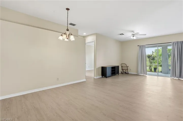 Unfurnished living room with light wood finished floors, a chandelier, and ceiling fan - Virtually Edited Image