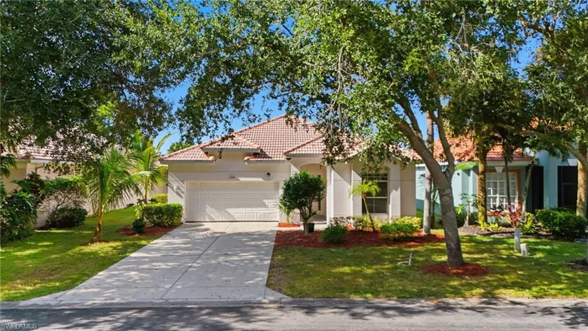 Mediterranean / spanish-style home with a tile roof, stucco siding, a garage, driveway, and a front lawn - Virtually Edited Image