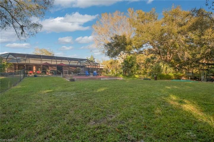 View from rear of yard facing deck with fireplace and fenced yard to the left.