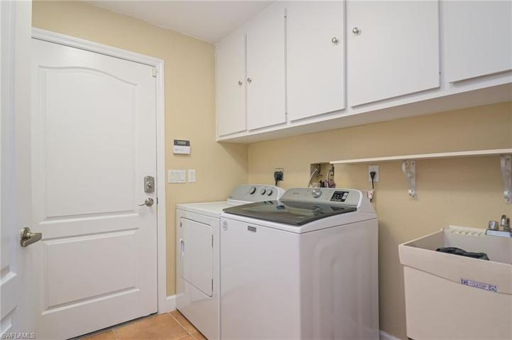 Enclosed laundry room with washer, dryer, sink and lots of cabinets.