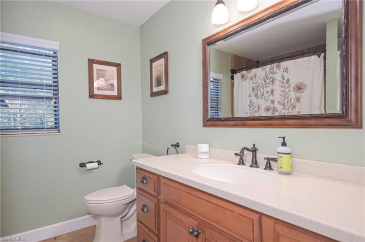 Guest bathroom with shower and tub, wood cabinetry and large oversized counter.