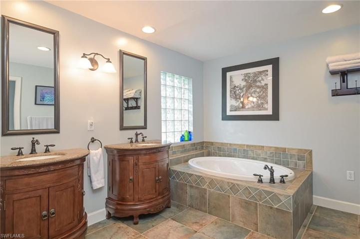 Luxurious Master Bath features double sinks, wood cabinetry and big tub with glass brick accent window.