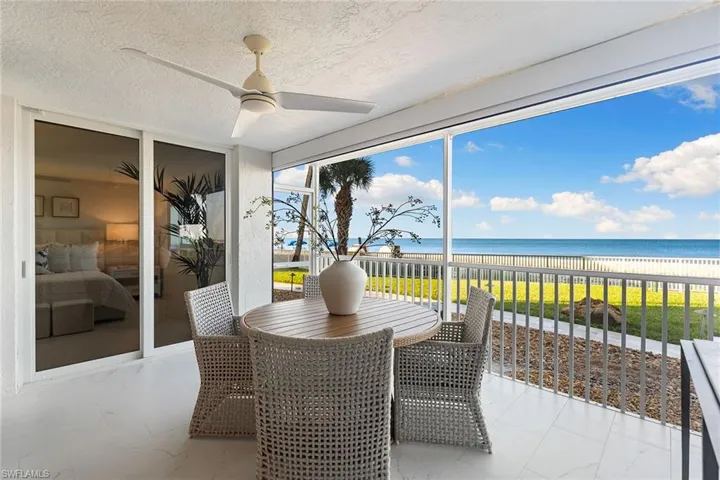 Sunroom with a water view, a textured ceiling, expansive windows, and marble look tile flooring
