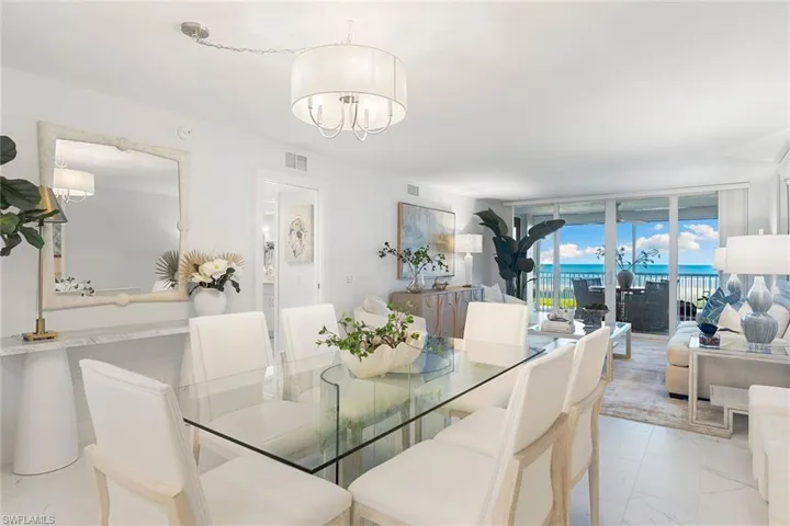Dining area featuring light tile floors, a wall of windows, and a chandelier