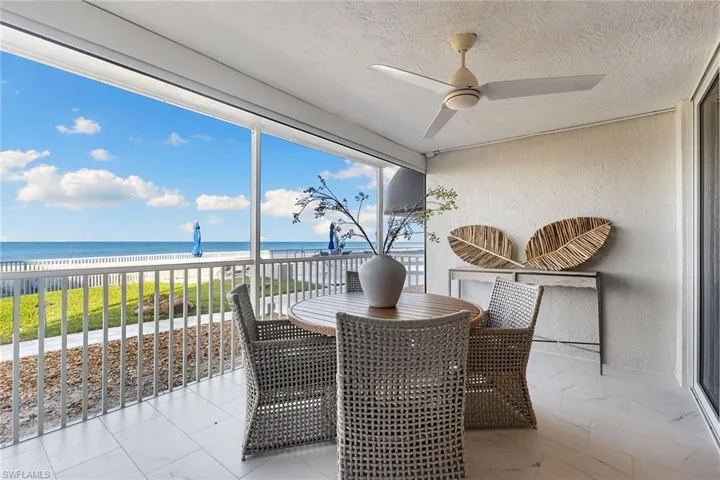 Sunroom featuring view of water and beach