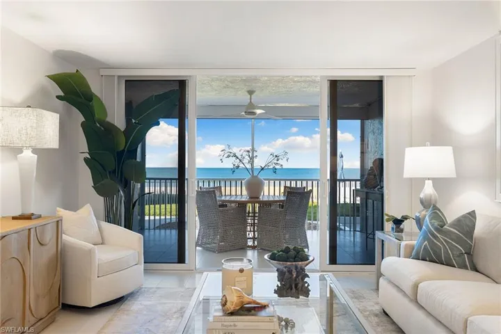 Living area with expansive windows, a water and beach views and nice natural light