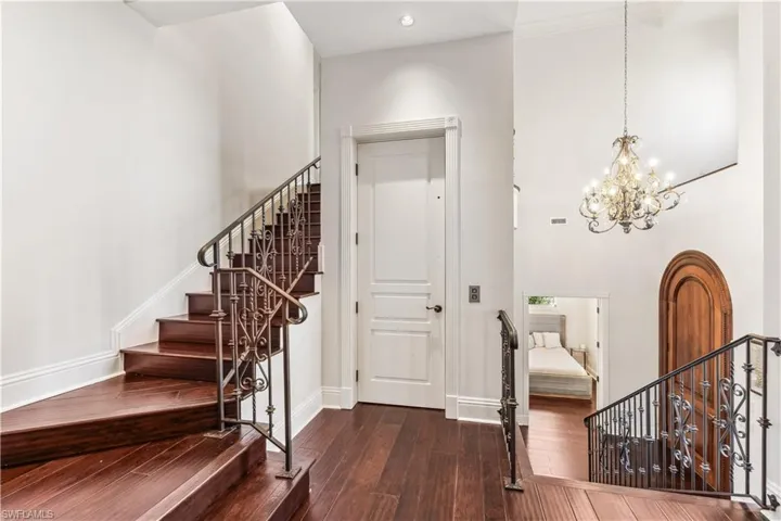 The entrance foyer on the second floor featuring a notable chandelier, a towering ceiling, and dark wood-type flooring