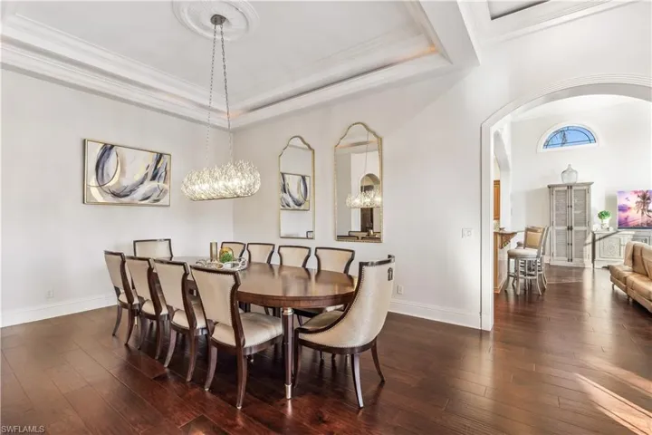 Dining room featuring dark hardwood / wood-style flooring, a tray ceiling, an inviting chandelier, and ornamental molding