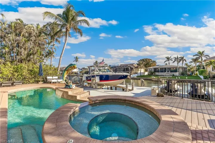 View of pool with a water view, an in-ground hot tub, and a dock