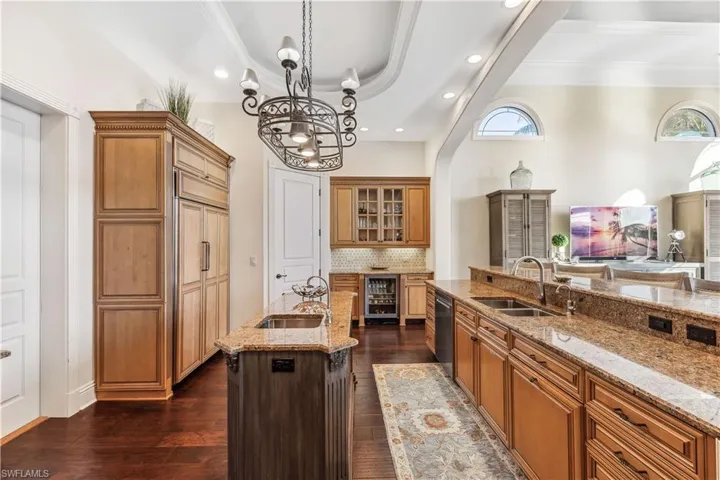 Kitchen with subzero refrigerator, stainless steel appliances, dark wood-type flooring, sink, pendant lighting, and a large island