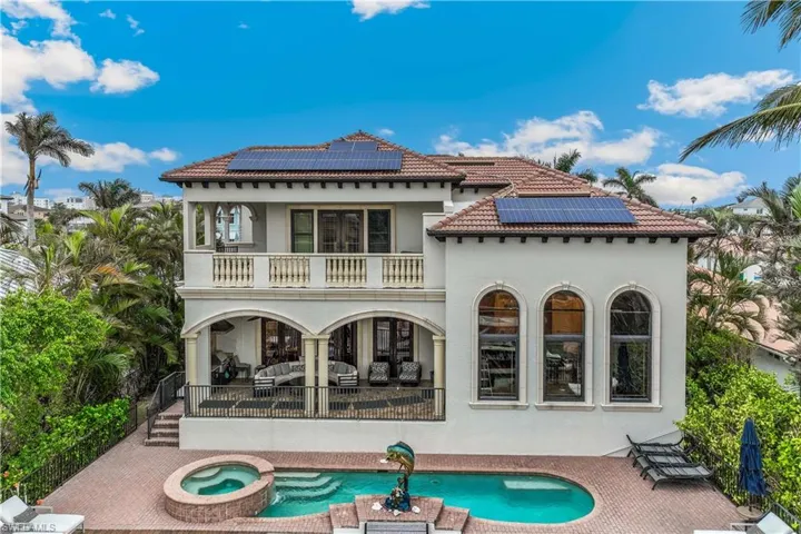 The back of the house features solar panels, a swimming pool with hot tub, a balcony, and a patio
