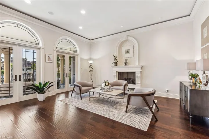Living area with ornamental molding, dark wood-type flooring, and french doors