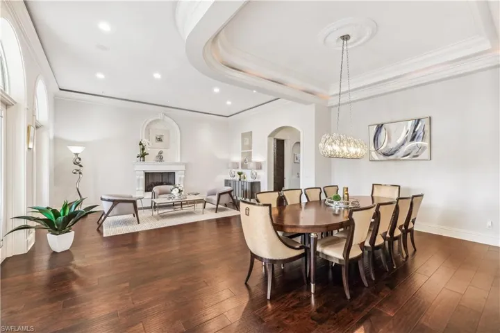 Dining room featuring ornamental molding, a tray ceiling, and dark wood-type flooring