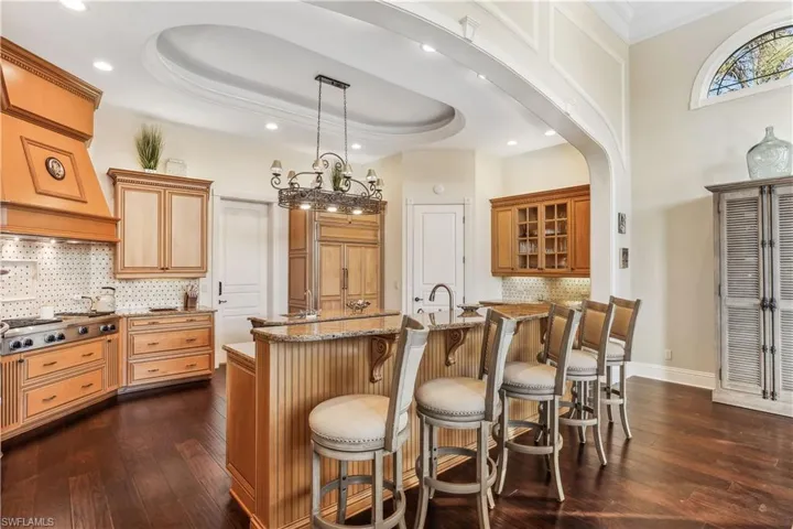 Breakfast Bar -  featuring backsplash, stainless steel gas stovetop, a raised ceiling, and dark wood-type flooring