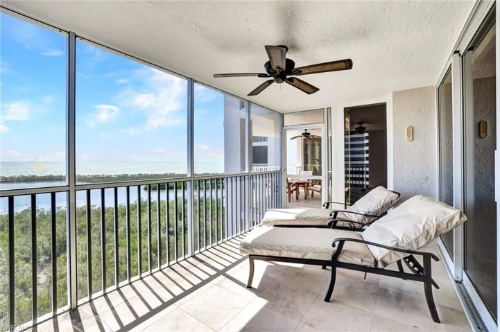 Sunroom / solarium featuring ceiling fan and a water view