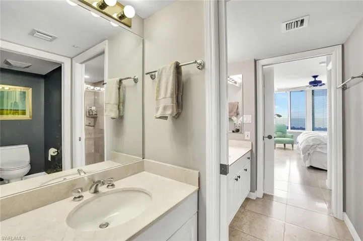 Ensuite bathroom with toilet, visible vents, tile patterned floors, and vanity