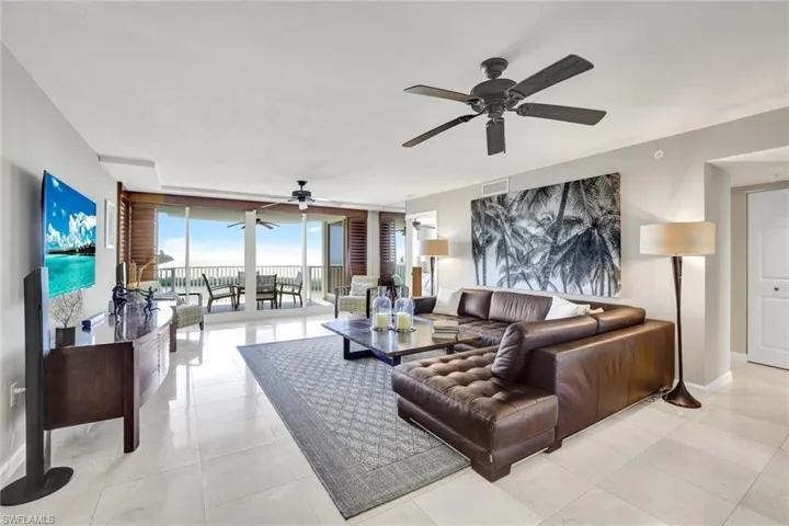 Living area featuring light tile patterned floors, expansive windows, a ceiling fan, visible vents, and baseboards