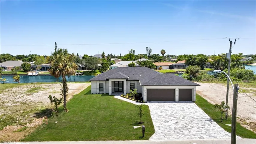 View of front facade featuring an attached garage, a residential view, decorative driveway, and a front yard