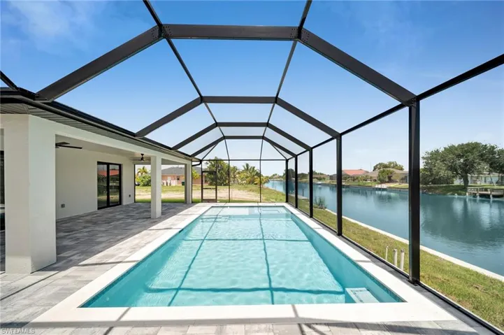 Swimming pool featuring a water view, a patio, and a lanai