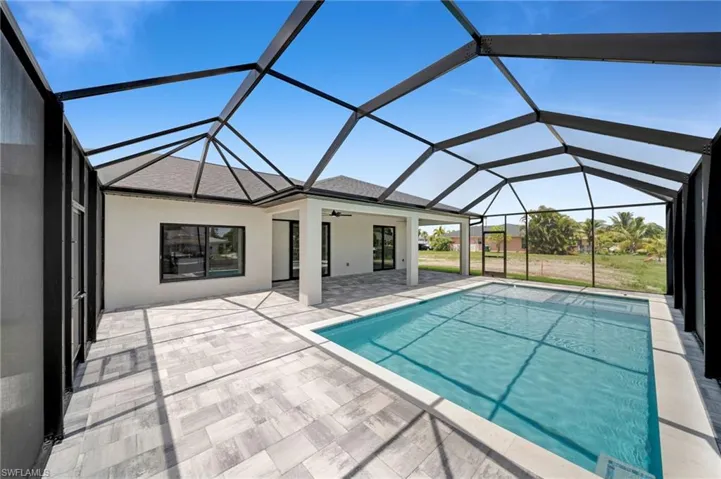 Outdoor pool with a patio area, ceiling fan, and glass enclosure