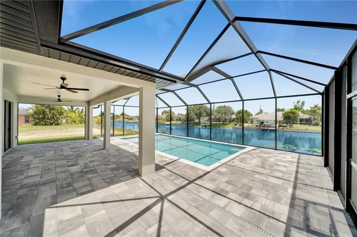 Swimming pool featuring a patio area, a water view, a ceiling fan, and glass enclosure
