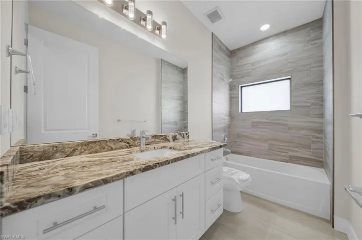 Full bath with vanity, washtub / shower combination, and recessed lighting