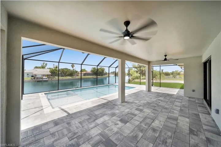 View of swimming pool featuring ceiling fan, a patio area, and glass enclosure