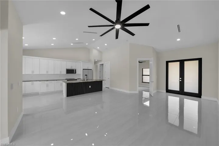 Unfurnished living room with french doors, ceiling fan, high vaulted ceiling, recessed lighting, and light tile patterned floors