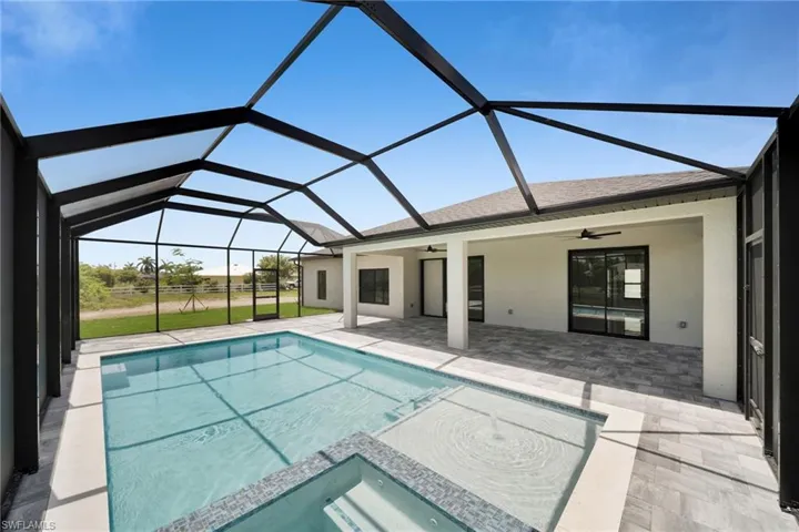 View of pool featuring a ceiling fan, a patio area, a pool with connected hot tub, and a lanai