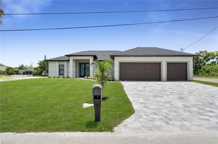 Prairie-style house with decorative driveway, a garage, a front yard, and stucco siding