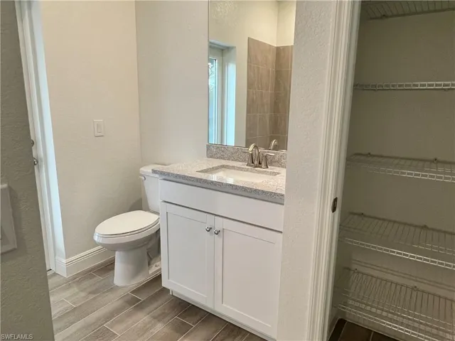 Bathroom with a textured wall, vanity, and wood finish floors