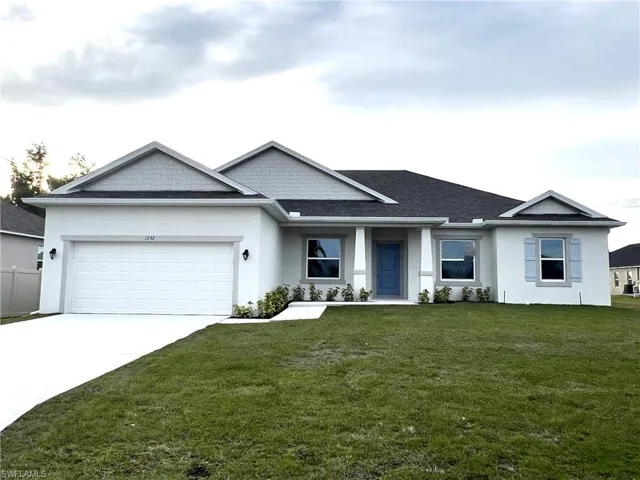 View of front of property featuring a front lawn, stucco siding, a garage, and concrete driveway