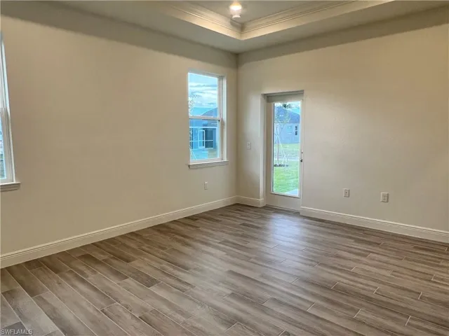 Empty room featuring ornamental molding, wood finish floors, and a raised ceiling