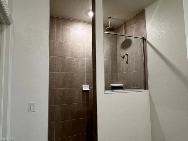 Full bath with a textured wall and a walk in shower
