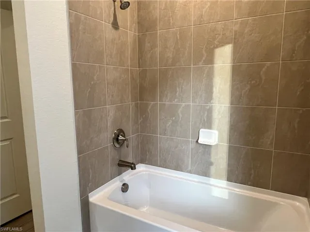 Bathroom with shower / tub combination and a textured wall