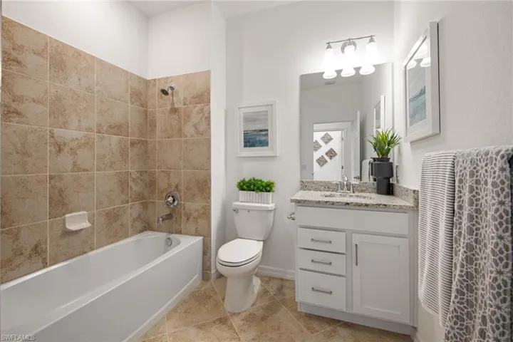 Bathroom featuring toilet, vanity, baseboards, and shower / washtub combination