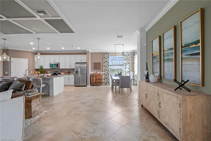 Kitchen featuring visible vents, white cabinets, open floor plan, crown molding, and stainless steel appliances