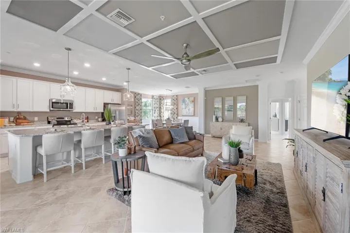 Living area with light tile patterned floors, ornamental molding, a ceiling fan, visible vents, and coffered ceiling